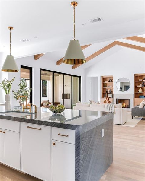 Kitchen with light hardwood / wood-style flooring, white cabinetry, lofted ceiling with beams, and pendant lighting