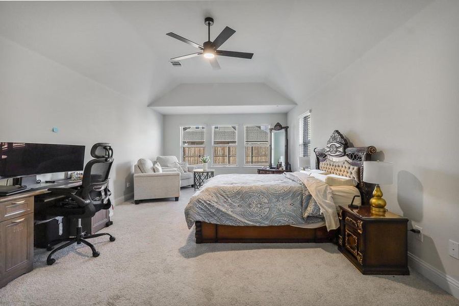Bedroom featuring an office area, light carpet, ceiling fan, and vaulted ceiling