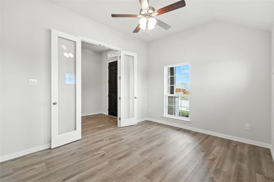 Unfurnished room featuring ceiling fan, light wood-type flooring, and vaulted ceiling