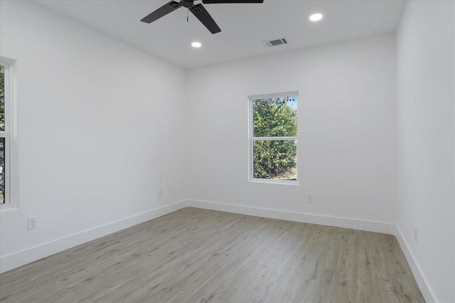 Empty room with ceiling fan and light wood-type flooring