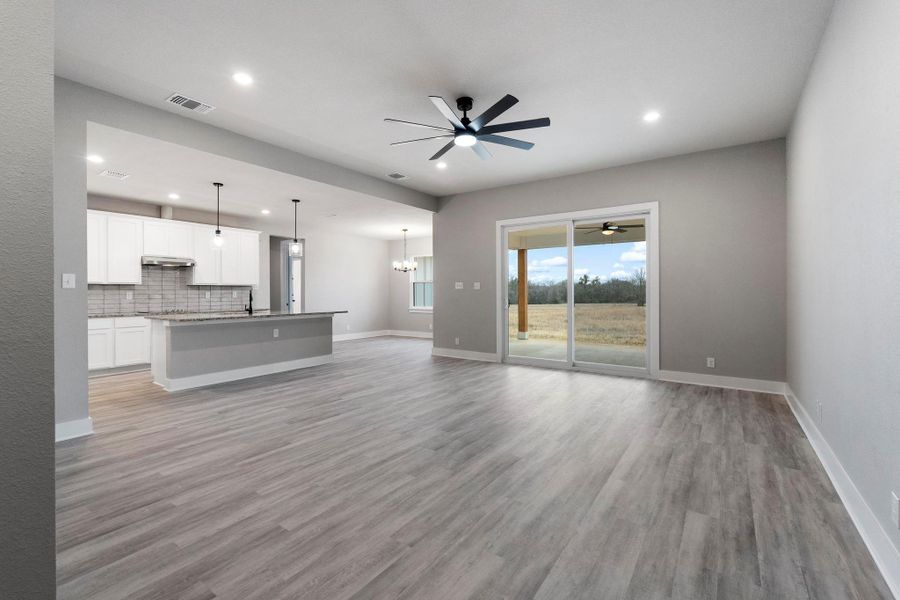 Unfurnished living room featuring a ceiling fan, a chandelier, light wood-type flooring, and recessed lighting