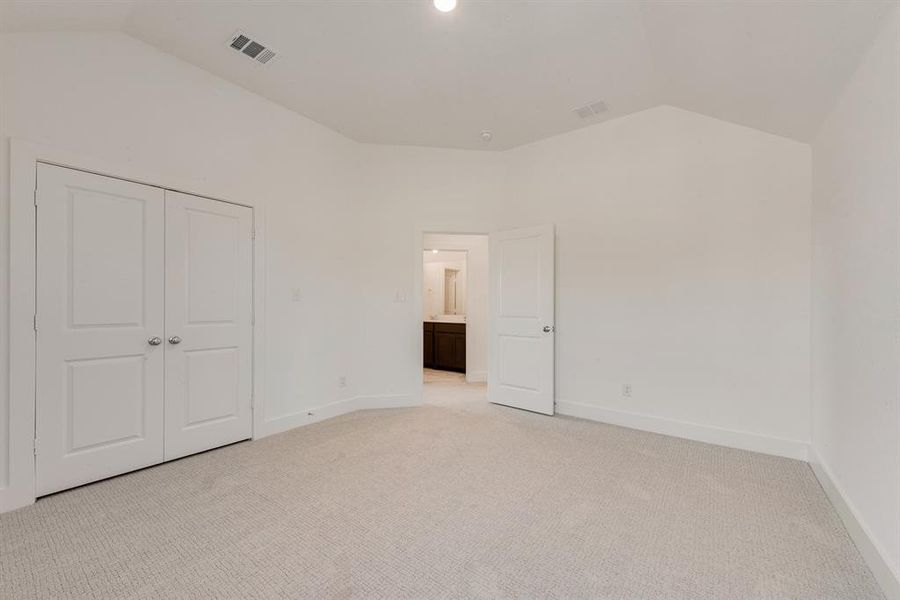 Unfurnished bedroom featuring light carpet, lofted ceiling, and a closet Unfurnished bedroom featuring light carpet, lofted ceiling, and a closet