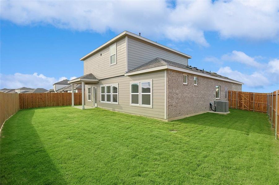 Rear view of house featuring a yard and central air condition unit