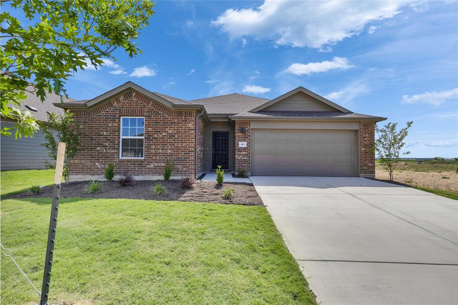 Single story home featuring a garage, concrete driveway, brick siding, and a front lawn