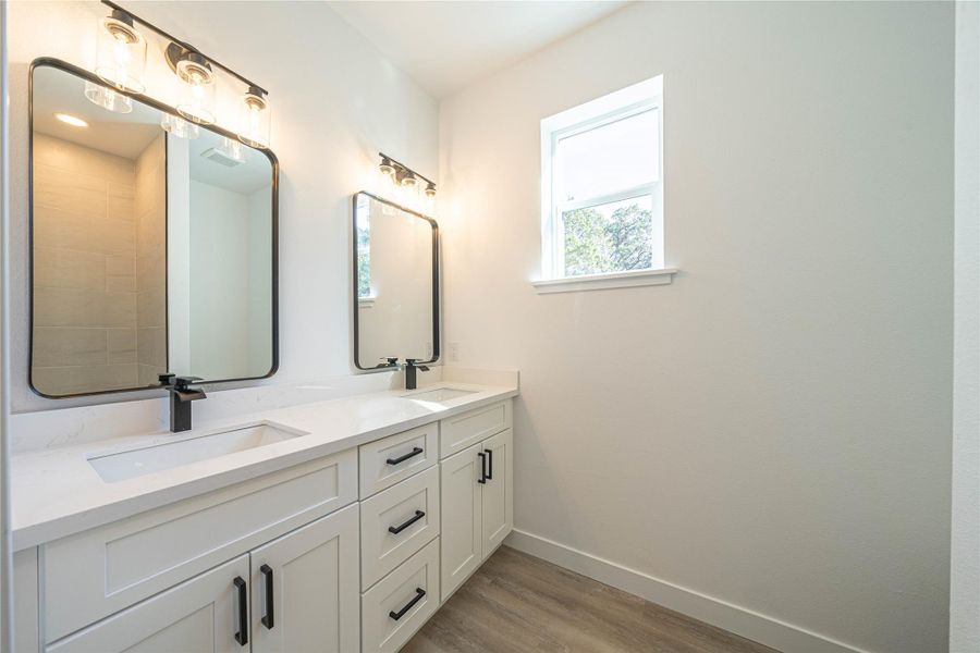 Bathroom with double vanity and light wood-style flooring