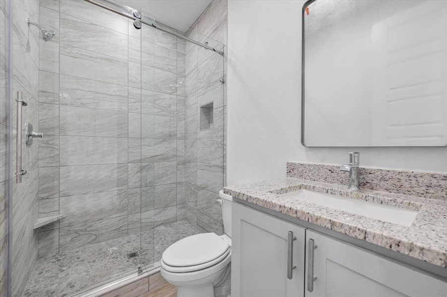 Bathroom with vanity, toilet, and a shower with shower door