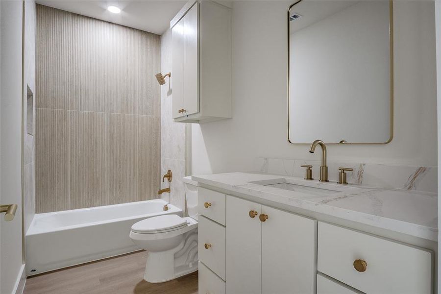 Full bathroom with wood finished floors, vanity, and shower / washtub combination Full bathroom with wood finished floors, vanity, and shower / washtub combination