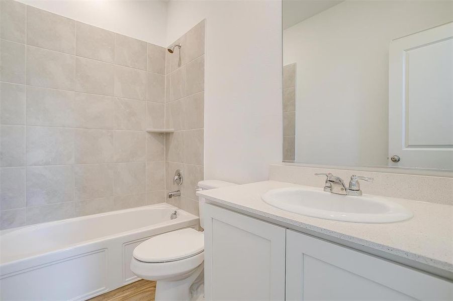 Full bathroom with vanity, tiled shower / bath, wood-type flooring, and toilet