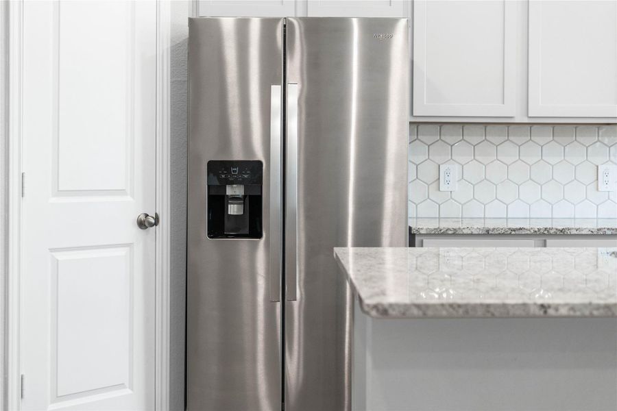 Kitchen comes equipped with a side-by-side Whirlpool refrigerator.