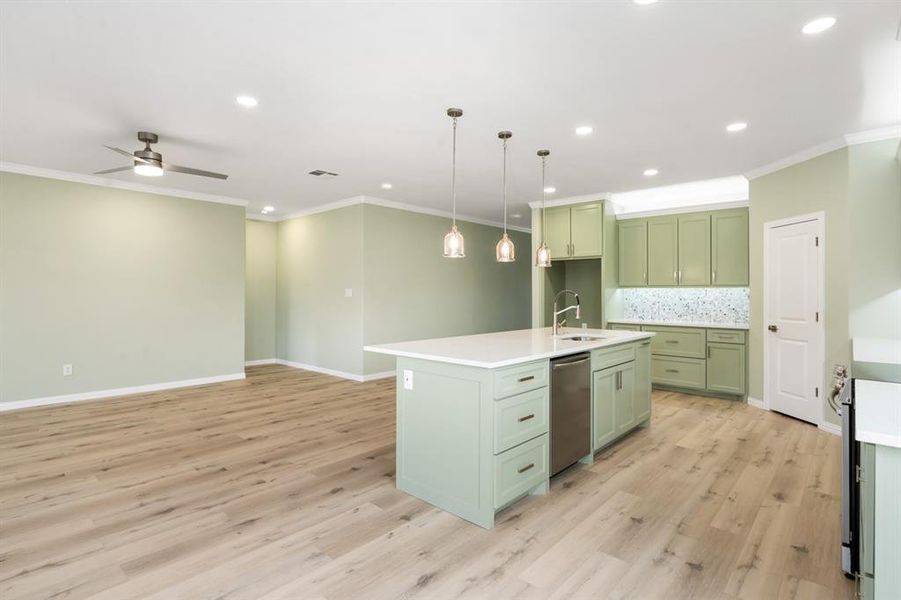 Kitchen featuring light hardwood / wood-style flooring, a center island with sink, green cabinetry, dishwasher, and ceiling fan