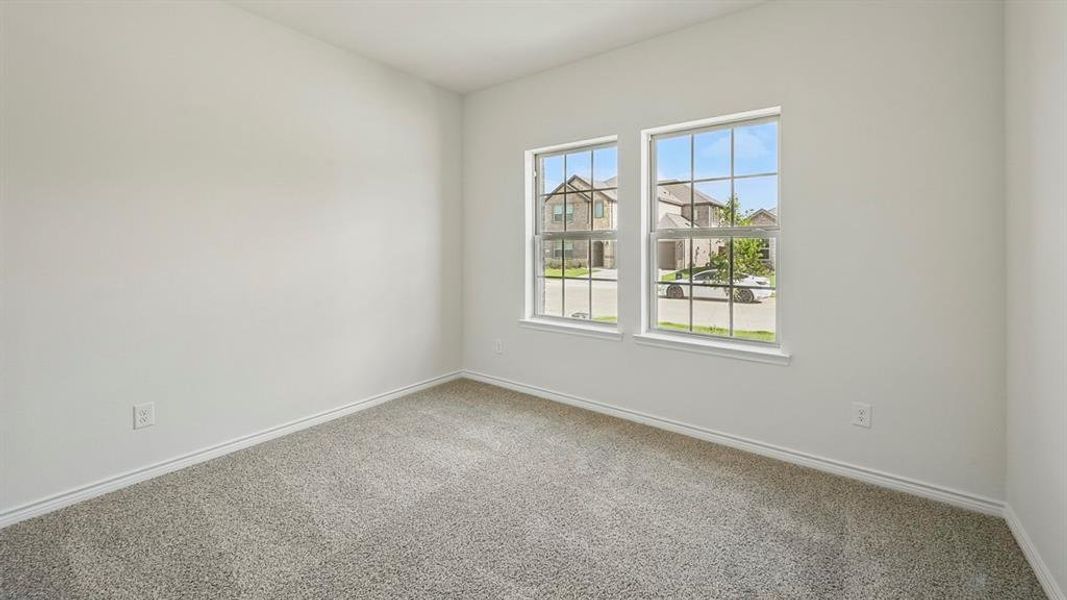 Neutral-toned interior room featuring two large windows with grid patterns, light gray carpeting, crisp white walls, and matching white baseboards Neutral-toned interior room featuring two large windows with grid patterns, light gray carpeting, crisp white walls, and matching white baseboards