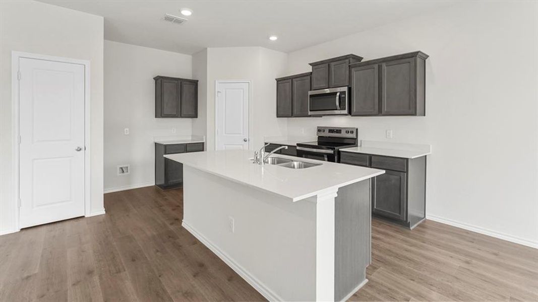 The kitchen features an island with a sink, white countertops, and dark wood cabinetry