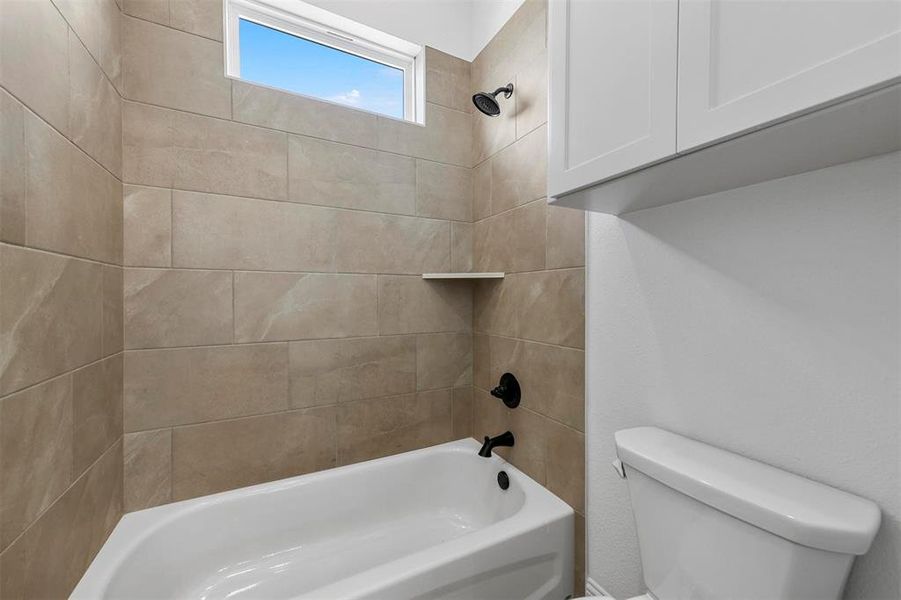 Bathroom featuring tiled shower / bath and toilet