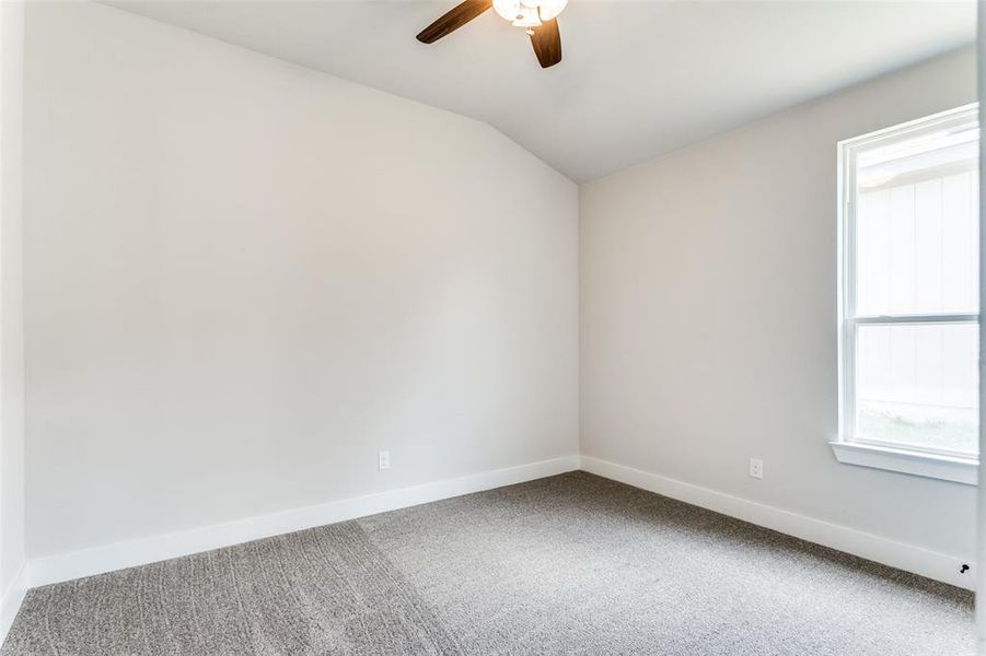 Spare room featuring carpet flooring, lofted ceiling, and ceiling fan