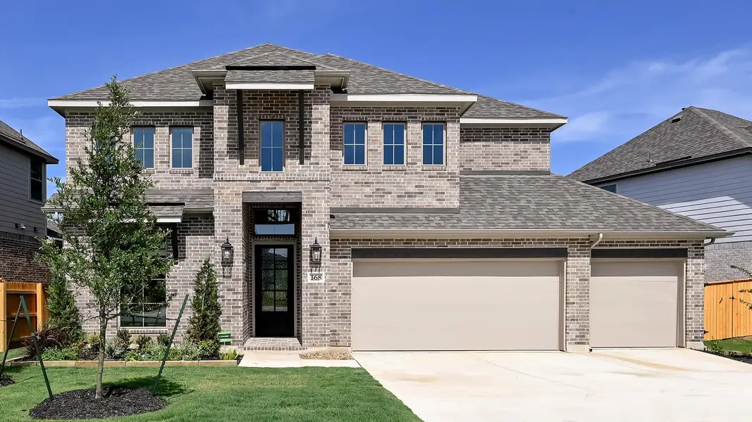 View of front of home with a shingled roof, driveway, brick siding, and an attached garage