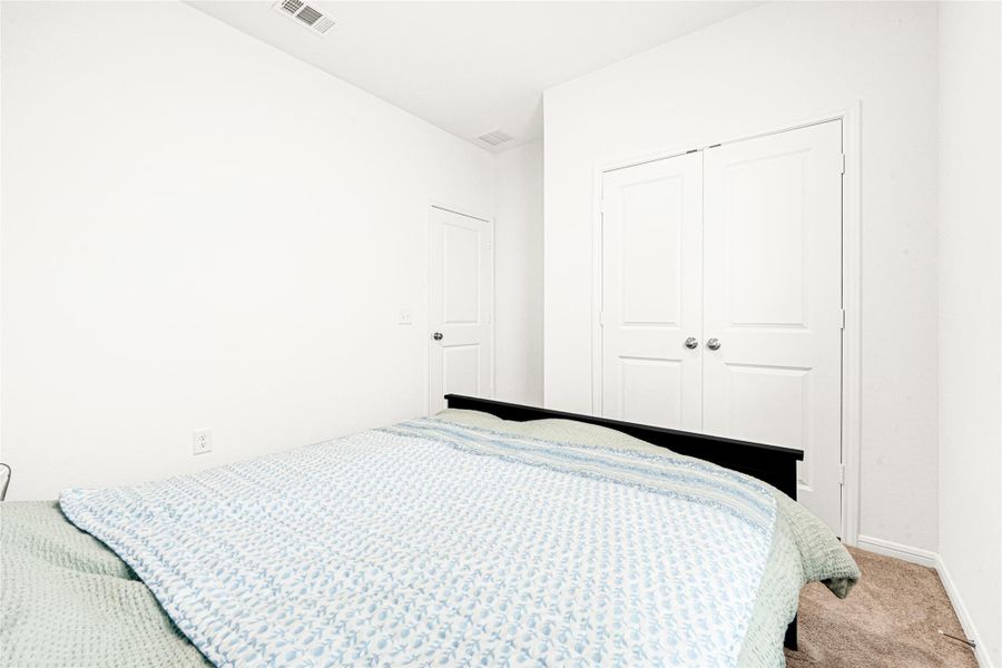 Another view of the comfortable secondary bedroom, featuring soft neutral carpet and plenty of room.