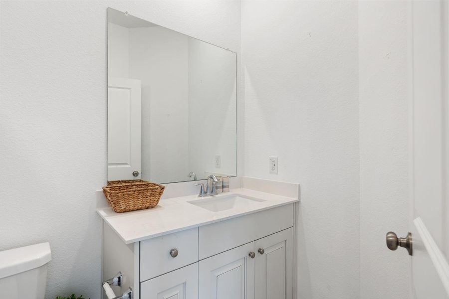 Upstairs bathroom has a shower/tub combo and a white vanity with solid surface countertop and undermount sink.