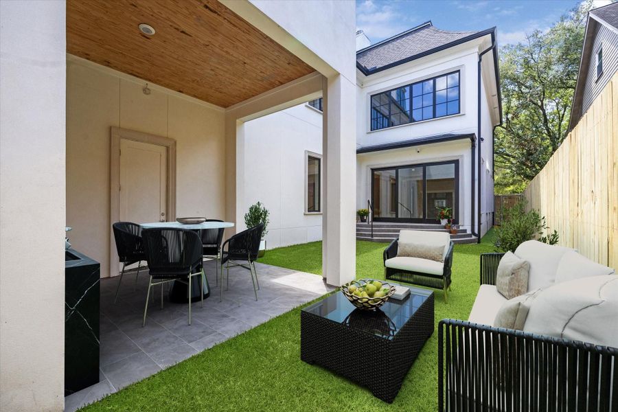 Relaxing or entertaining in this inviting backyard with a cozy outdoor seating area, covered patio for dining, and vibrant green grass. The covered area is ready for you to install your own kitchen equipment or if you want, possibly think even a small pool for those sunny summer days!  This photo has been virtually staged.