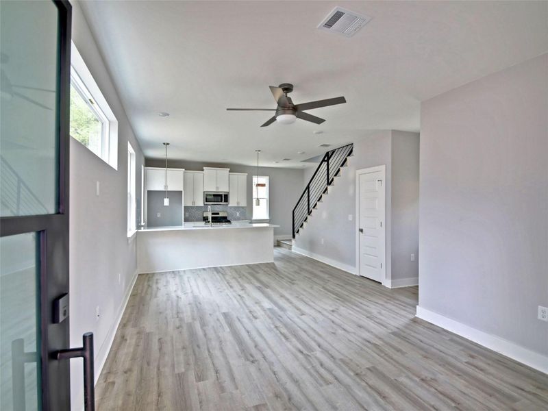 Unfurnished living room featuring stairs, light wood finished floors, and ceiling fan