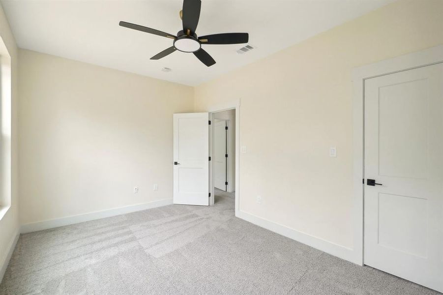 Unfurnished bedroom with light carpet and ceiling fan