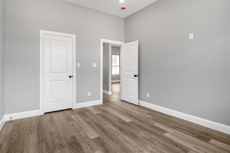 Unfurnished bedroom featuring wood finished floors and a towering ceiling Unfurnished bedroom featuring wood finished floors and a towering ceiling