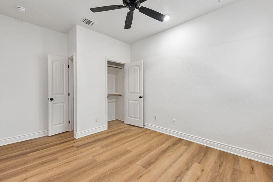 A pristine bedroom showcasing durable wood-look flooring and a convenient built-in closet. A pristine bedroom showcasing durable wood-look flooring and a convenient built-in closet.