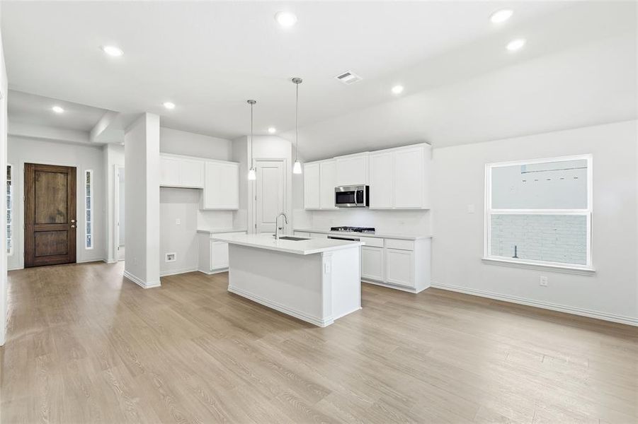 Kitchen featuring recessed lighting, a kitchen island with sink, white cabinetry, light wood-style flooring, and hanging light fixtures