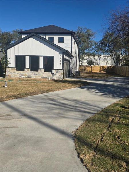 View of side of home with board and batten siding, stone siding, and concrete driveway View of side of home with board and batten siding, stone siding, and concrete driveway