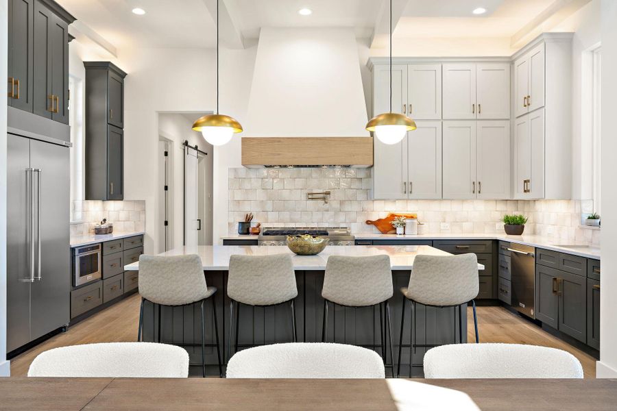 Kitchen with tasteful backsplash, a barn door, light wood-style flooring, stainless steel appliances, and premium range hood