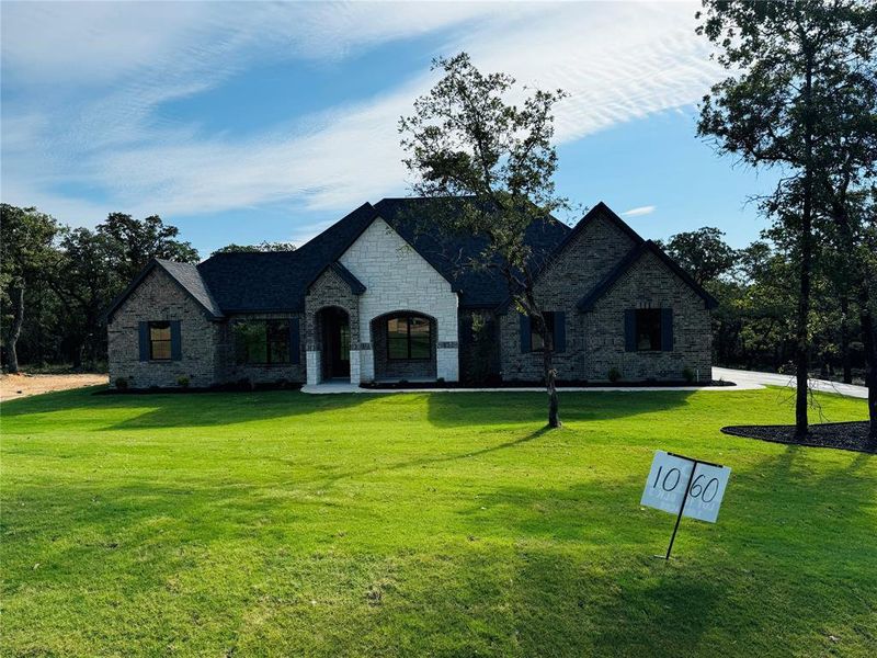 French country style house with stone siding and a front lawn French country style house with stone siding and a front lawn