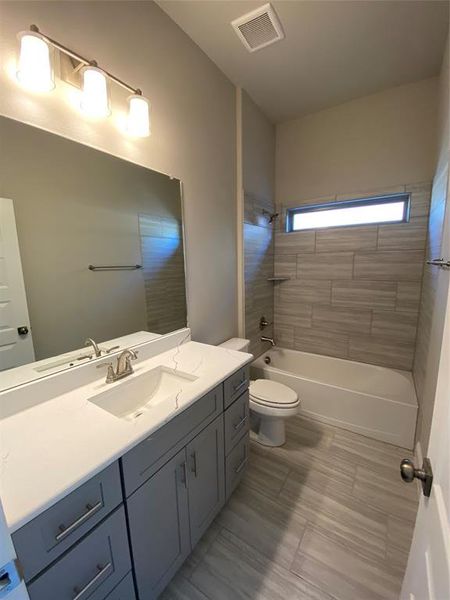 Bath 2 with 12x24 tile on floor & shower walls, Quartz countertops, and shower/tub combo with window.