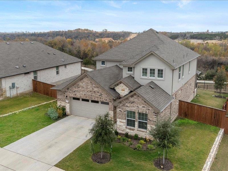 View of front facade with roof with shingles, driveway, brick siding, a garage, and stucco siding