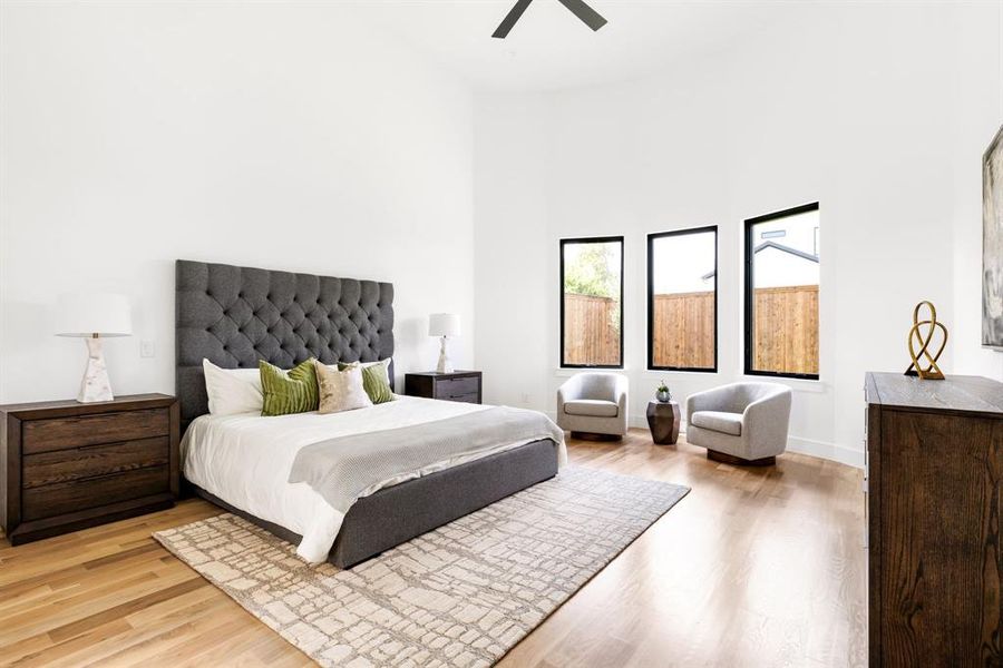 Bedroom with light wood-style flooring, a high ceiling, and ceiling fan Bedroom with light wood-style flooring, a high ceiling, and ceiling fan
