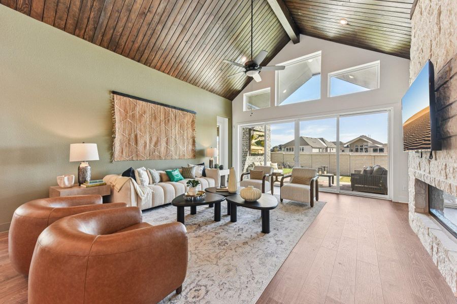 Rich wood planking accents a soaring vaulted ceiling above the stone fireplace and wide glass doors.
