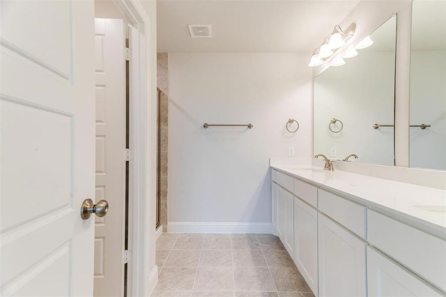 Full bathroom featuring double vanity, a shower stall, and light tile patterned floors