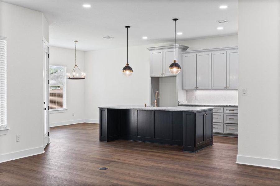 The kitchen features a dark-toned island with a light-colored countertop, complemented by light gray cabinetry and a white subway tile backsplash