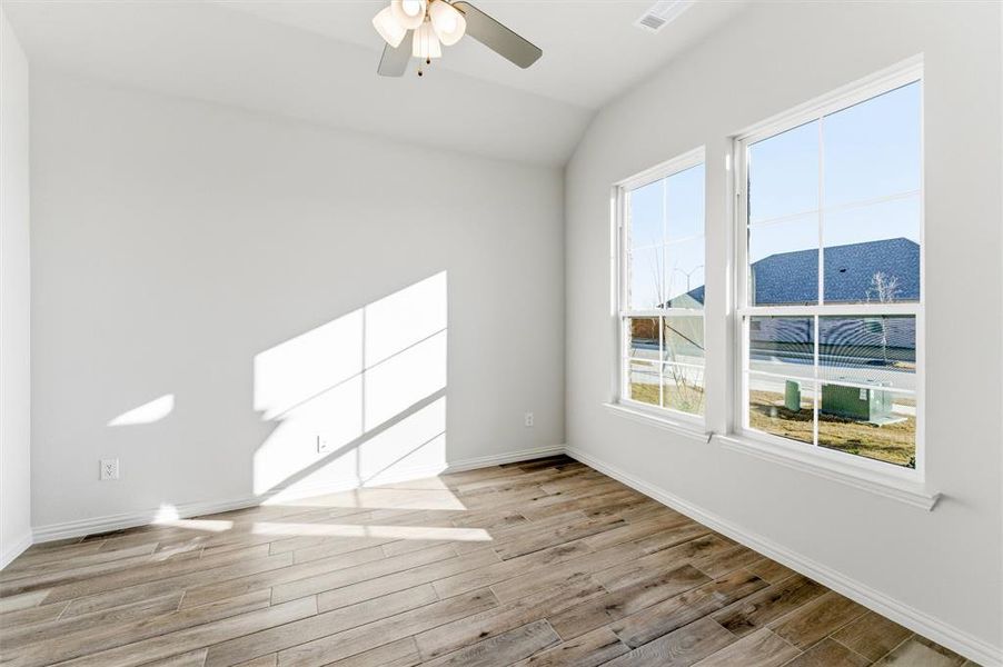 Spare room featuring light wood-style floors, lofted ceiling, and ceiling fan