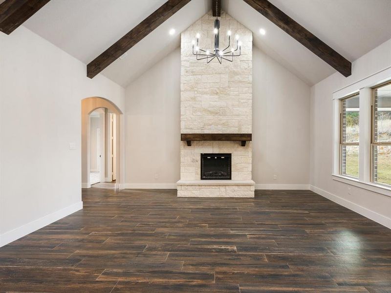 Unfurnished living room featuring a chandelier, beamed ceiling, and dark wood-type flooring