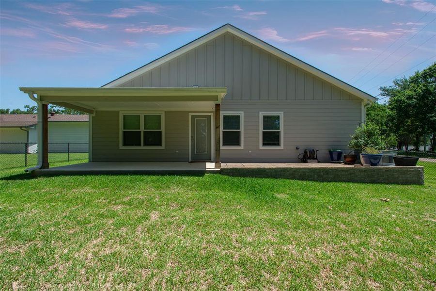 Back of property at dusk with board and batten siding and a patio area Back of property at dusk with board and batten siding and a patio area