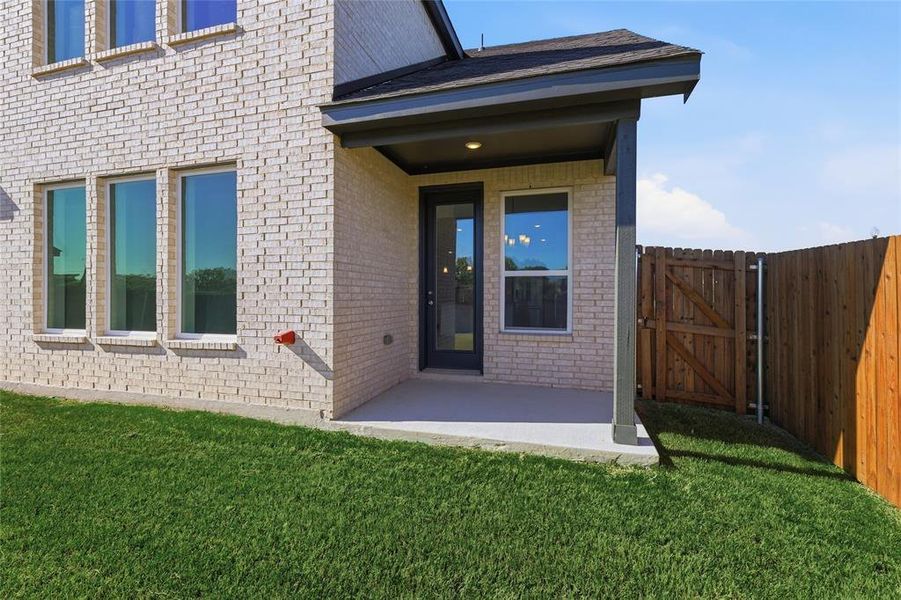 Property entrance with a patio area, brick siding, a yard, and a gate Property entrance with a patio area, brick siding, a yard, and a gate
