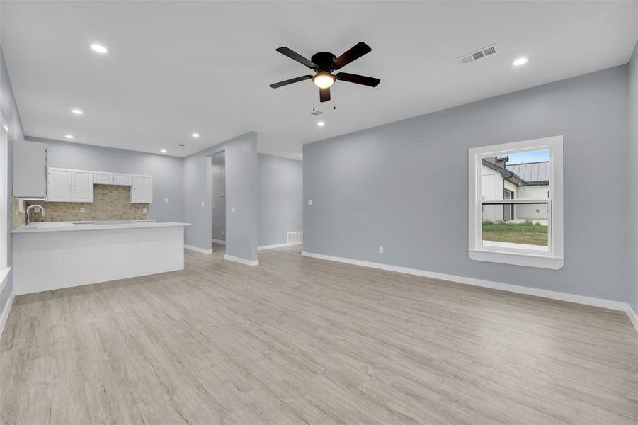 Unfurnished living room featuring a ceiling fan, light wood finished floors, and recessed lighting