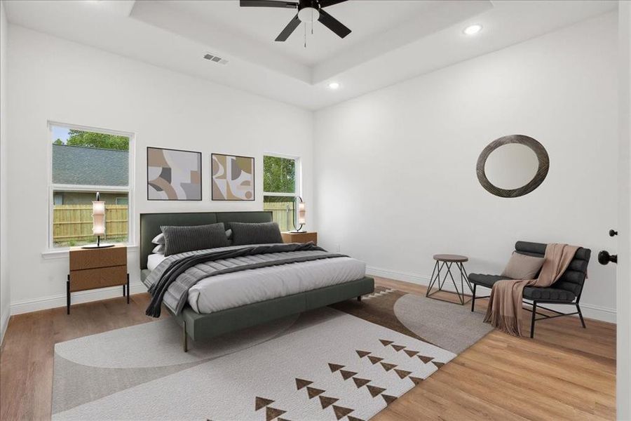 Bedroom with a tray ceiling, ceiling fan, and light hardwood / wood-style flooring