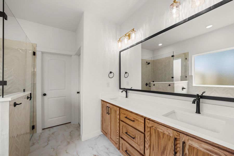 A well-lit primary bathroom featuring a spacious double vanity and elegant tile flooring. A well-lit primary bathroom featuring a spacious double vanity and elegant tile flooring.