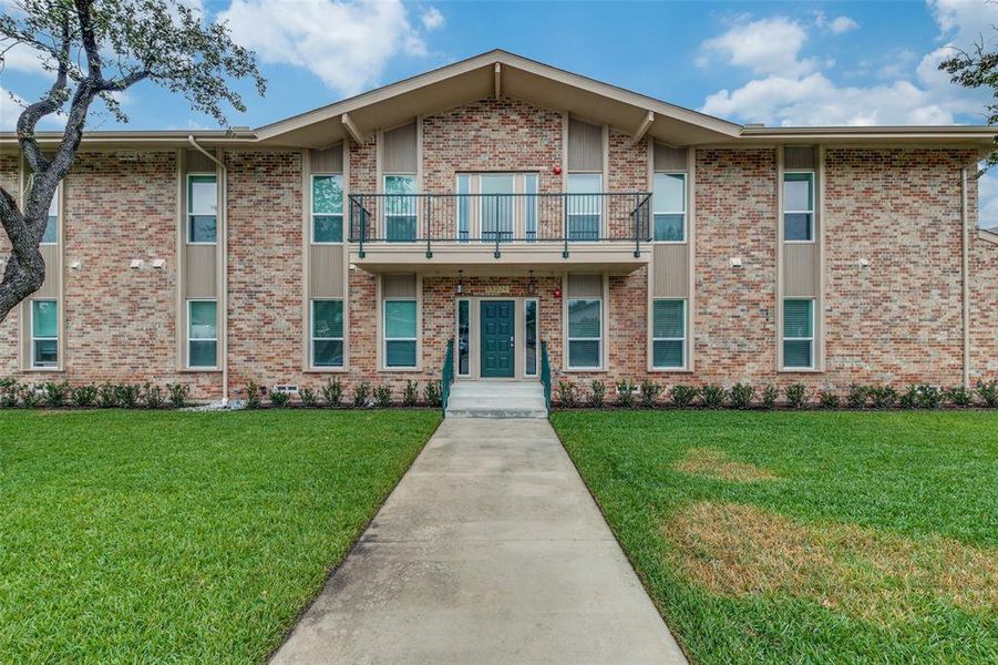 View of front of property featuring a front yard and a balcony