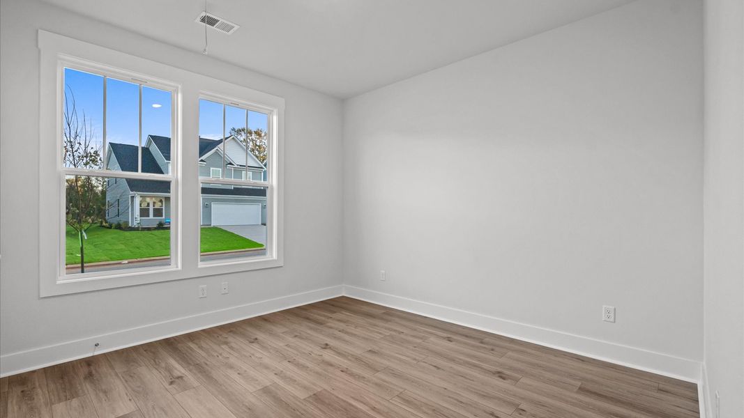 Elegant hardwood floors extend into spacious, light-filled secondary bedrooms