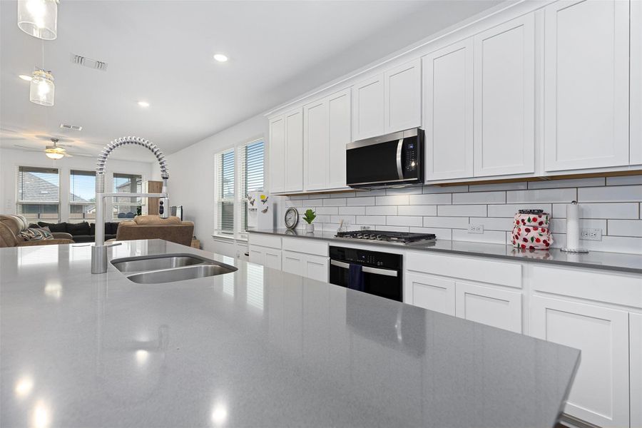 Kitchen featuring open floor plan, white cabinetry, dark stone counters, backsplash, and recessed lighting