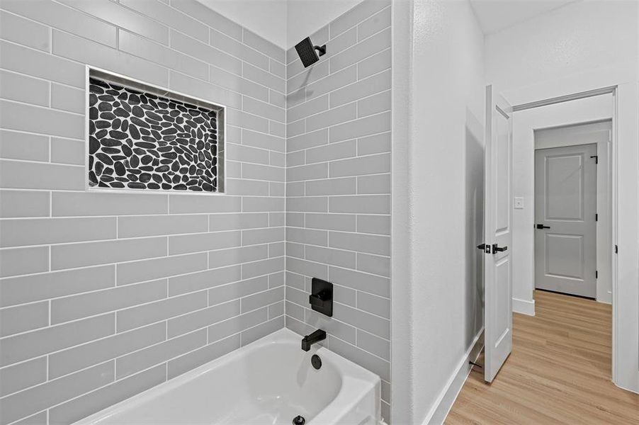 Bathroom with hardwood / wood-style floors and tiled shower / bath combo