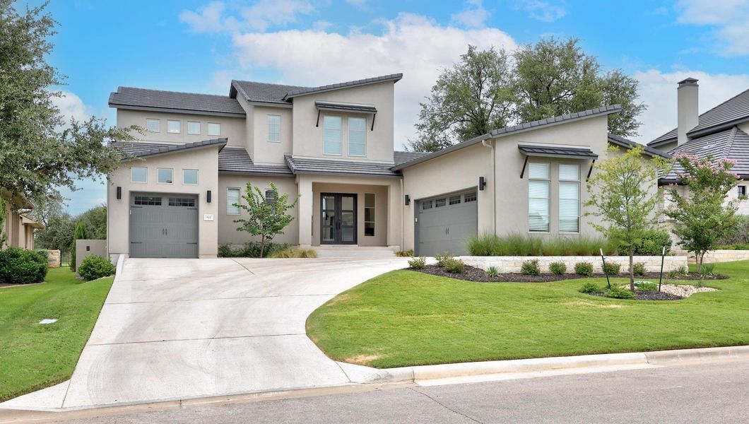 View of front of house featuring concrete driveway, stucco siding, a front lawn, and an attached garage