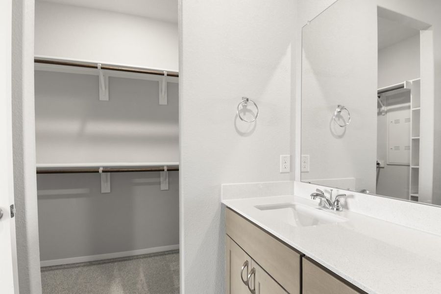 Image of primary bathroom with a mirror and vanity with a connected walk in closet