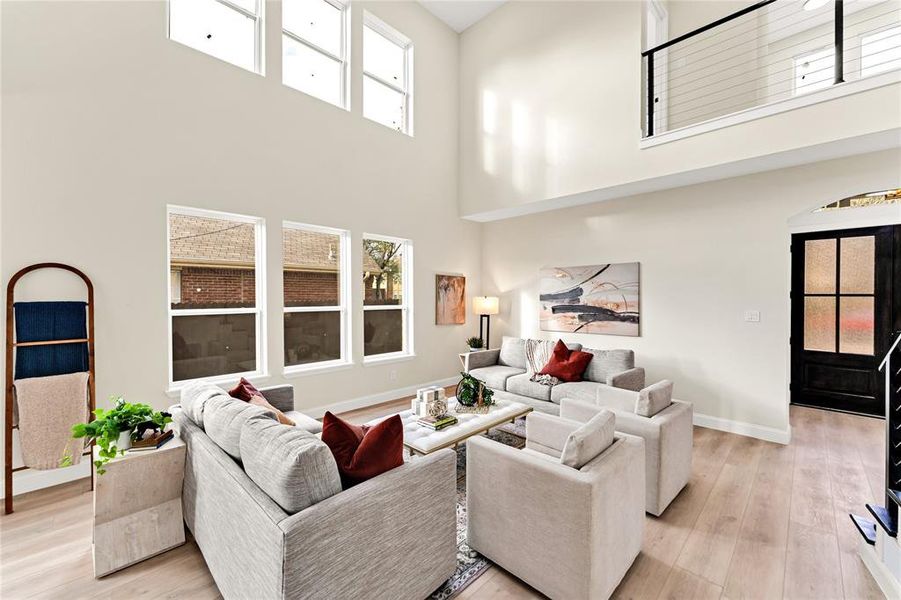 Living room with light hardwood / wood-style floors and a towering ceiling